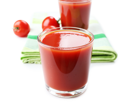 Glasses of fresh tomato juice on checkered napkin, isolated on whiteの写真素材