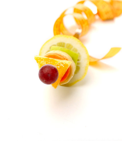 Snack of fruits on fork with measuring tape isolated on whiteの写真素材