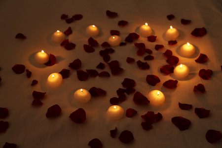 Heart of candles and red petals on bed, close upの写真素材