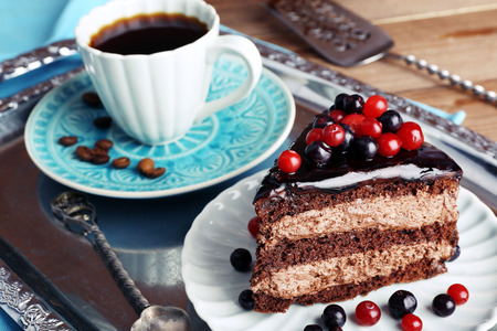 Delicious chocolate cake with berries and cup of coffee on table close upの写真素材