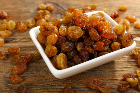Raisins in saucer on wooden table, closeupの写真素材