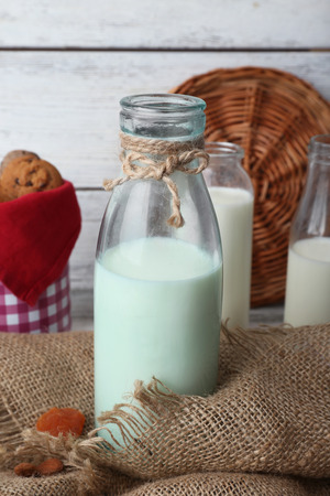 Milk in glassware and walnuts on wooden table with sackcloth, closeupの写真素材