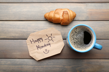 Cup of coffee with fresh croissant and Happy Monday massage on wooden backgroundの写真素材