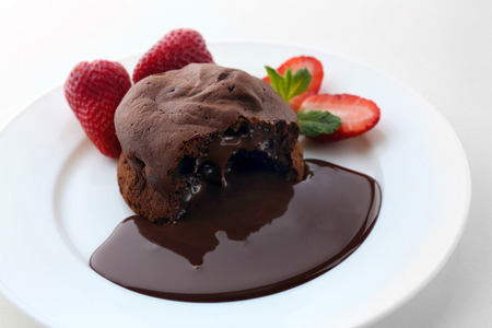 Chocolate fondant with strawberries on white plate, closeupの写真素材