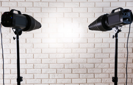 Photo studio with lighting equipment on brick wall background
