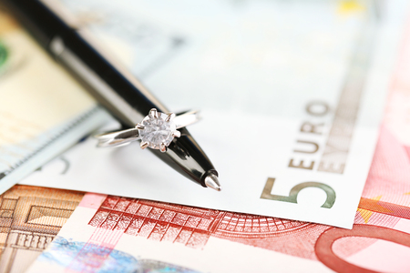 Wedding ring on pen, on banknotes background. Marriage of convenienceの写真素材