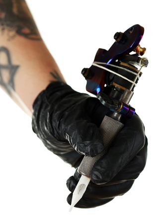 Hand of tattoo artist with tattoo machine isolated on whiteの写真素材