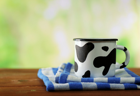 Mug of milk on wooden table, on green nature backgroundの写真素材