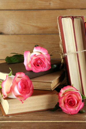 Tied books with pink roses on wooden backgroundの写真素材