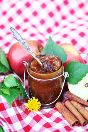 Apple jam in jar and fresh red apples outdoorsの写真素材