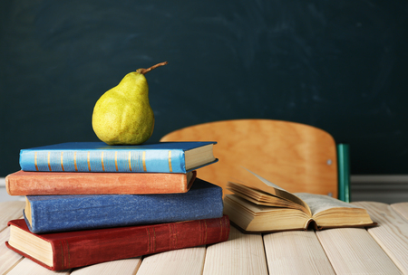 Stack of books on desk, on blackboard backgroundの写真素材