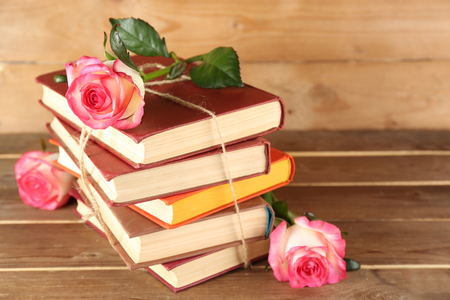 Tied books with pink roses on wooden backgroundの写真素材