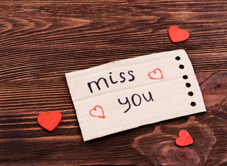 Inscription MISS YOU on cutout carton on wooden backgroundの写真素材