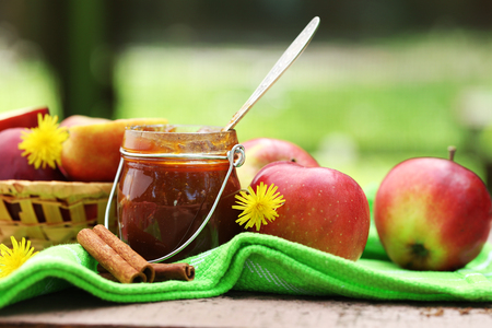 Apple jam in jar and fresh red apples outdoorsの写真素材