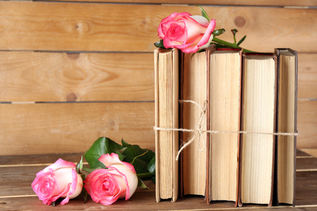 Tied books with pink roses on wooden backgroundの写真素材