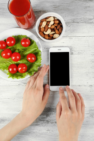 Food and mobile phone in female hands on wooden backgroundの写真素材