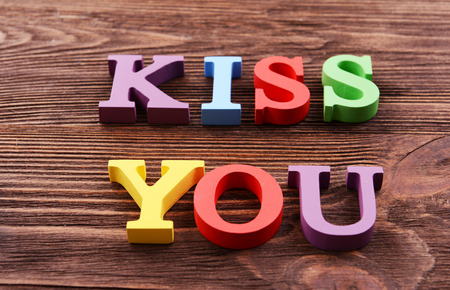Inscription KISS YOU made of colorful letters on wooden backgroundの写真素材