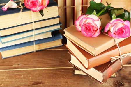 Tied books with pink roses on wooden backgroundの写真素材
