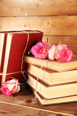 Tied books with pink roses on wooden backgroundの写真素材