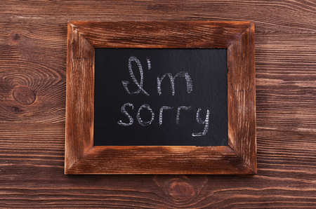 Inscription I'M SORRY on blackboard on wooden backgroundの写真素材