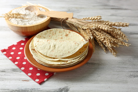 Stack of homemade whole wheat flour tortilla on plate, on wooden table backgroundの写真素材