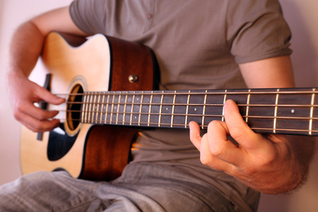 Young man playing on acoustic guitar close upの写真素材