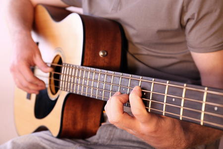 Young man playing on acoustic guitar close upの写真素材