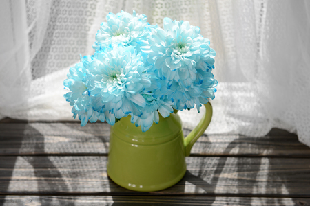 Beautiful chrysanthemums in pitcher on fabric backgroundの写真素材