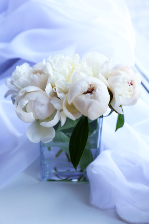 Beautiful white peonies in vase on fabric backgroundの写真素材