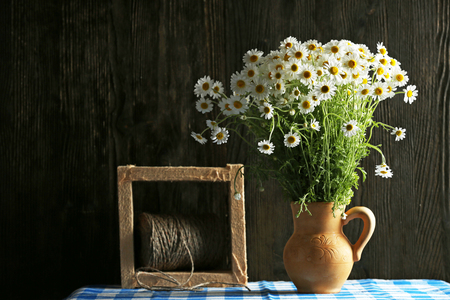 Beautiful bouquet of daisies in pitcher with twine on wooden backgroundの写真素材