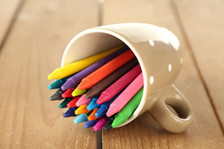 Colorful pastel crayons in cup on wooden backgroundの写真素材
