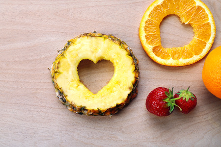 Fruits slices with cut in shape of heart and berries on table close upの写真素材