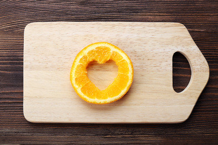 Orange slice with cut in shape of heart on wooden backgroundの写真素材