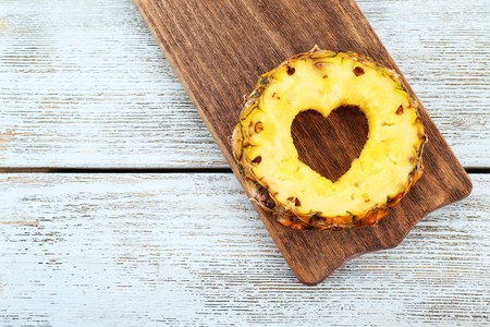 Pineapple slice with cut in shape of heart on wooden backgroundの写真素材