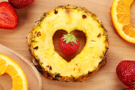 Fruits slices with cut in shape of heart and berries on table close upの写真素材