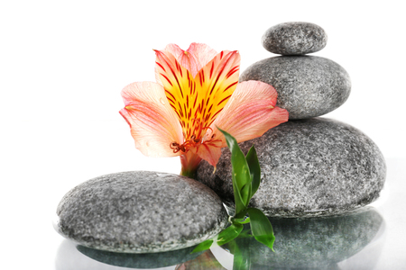 Stack of spa stones with flower isolated on whiteの写真素材