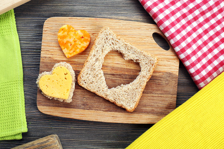 Bread slice with cut in shape of heart and cheese on table close upの写真素材