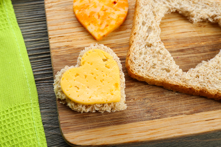 Bread slice with cut in shape of heart and cheese on table close upの写真素材