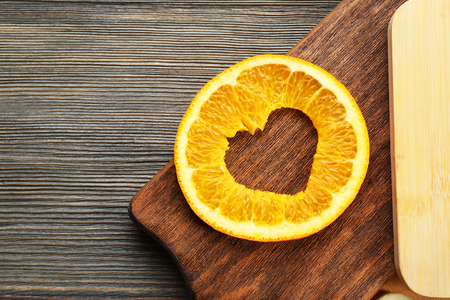 Orange slice with cut in shape of heart on wooden backgroundの写真素材