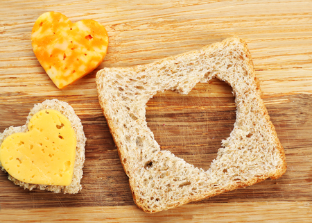 Bread slice with cut in shape of heart and cheese on wooden backgroundの写真素材