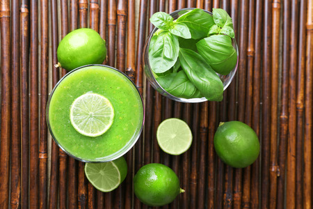 Glass of green healthy juice with basil and limes on table close upの写真素材