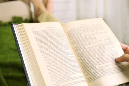 Young man reading book on sofa close upの写真素材