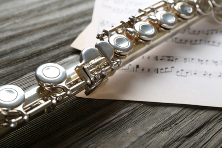 Silver flute with music notes on wooden table close upの写真素材