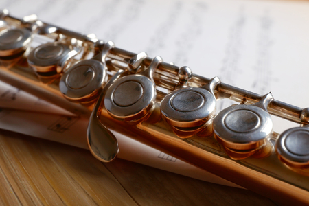 Silver flute with music notes on wooden table close upの写真素材