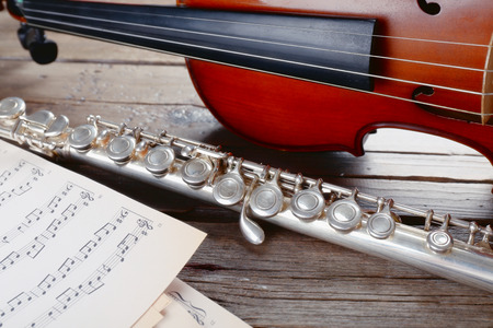 Flute and violin with music notes on wooden table close upの写真素材