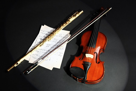 Violin and flute with music notes on dark backgroundの写真素材