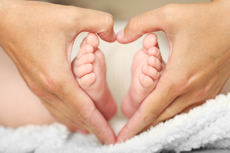 Adult hands holding baby feet, closeupの写真素材