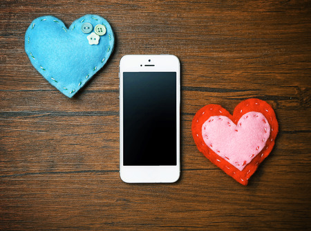 White smart phone with hearts on wooden desk.の写真素材