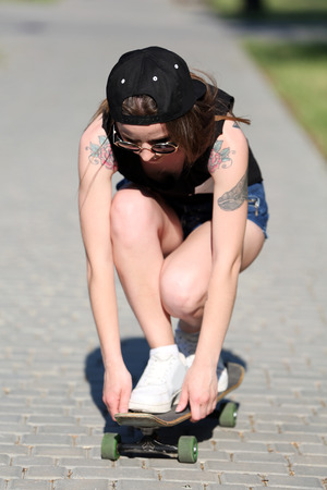 Beautiful tattooed girl with skateboard, outdoorsの写真素材