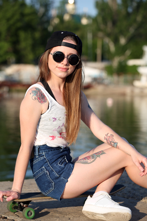Beautiful tattooed girl with skateboard, outdoorsの写真素材